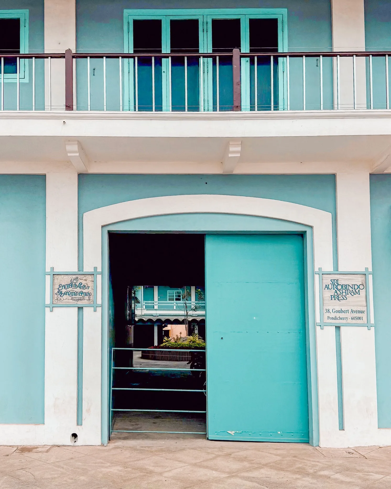 An aesthetic cafe interior at Coromandel Cafe Pondicherry with high ceilings, tropical plants, and marble tables.