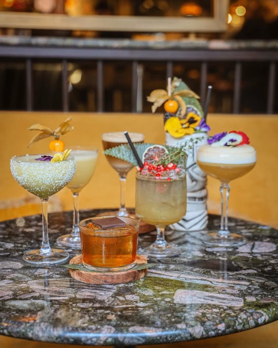 Decorative cocktails and a drink on a marble table in a softly lit bar