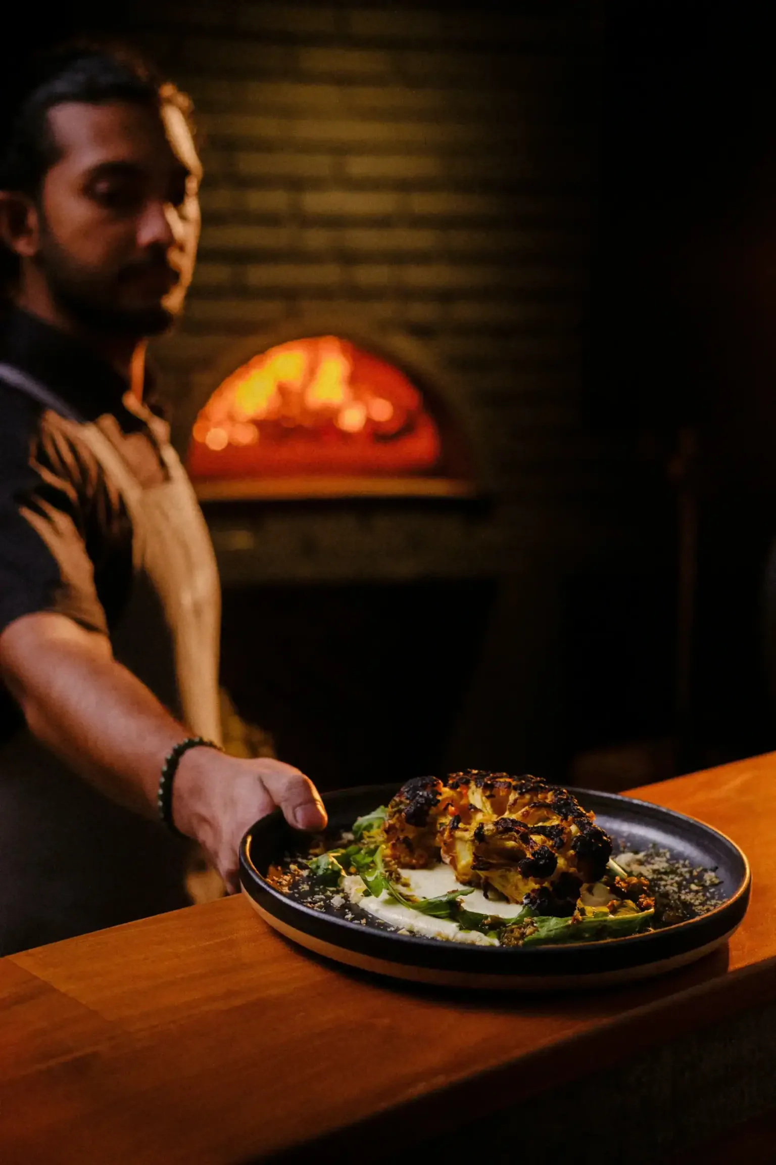 Chef serving a beautifully plated dish.