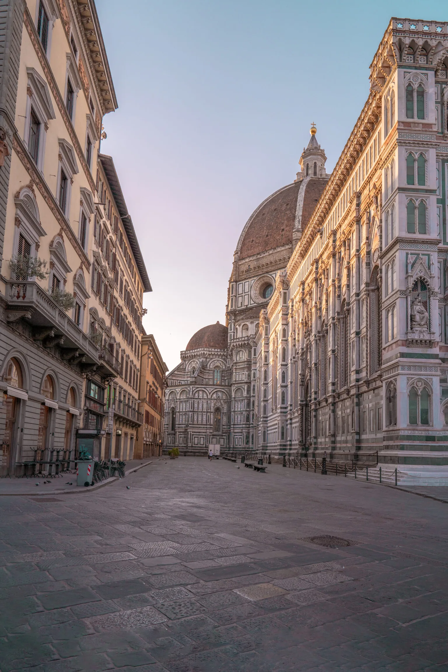 Florence's Duomo and ornate cathedral façade bathed in soft morning light above an empty cobblestone piazza.