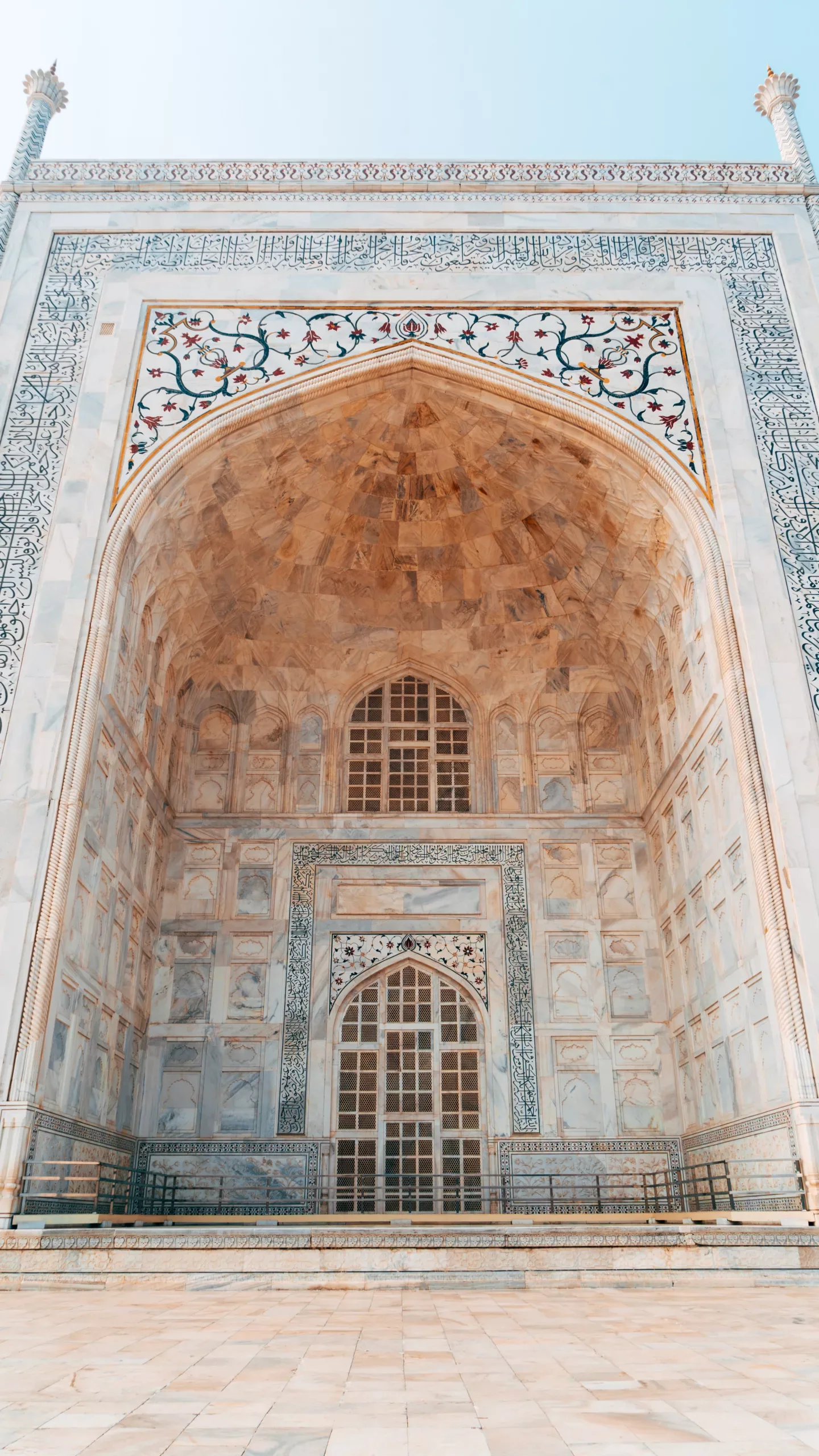 Ornate marble gateway with a large arched alcove, intricate floral inlay and lattice window typical of Mughal architecture.