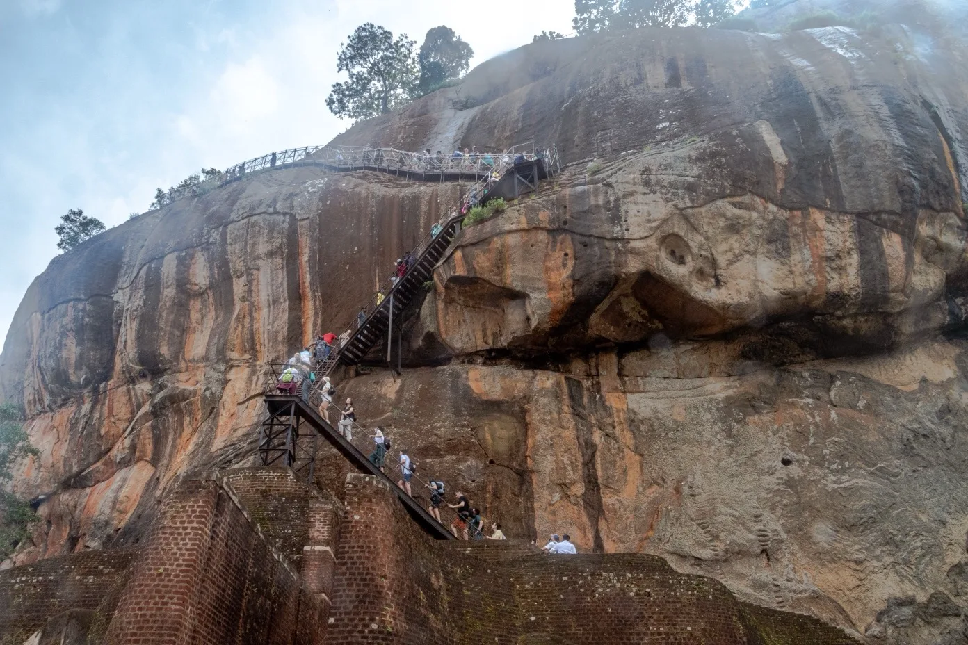Visitors climbing steep rock staircase