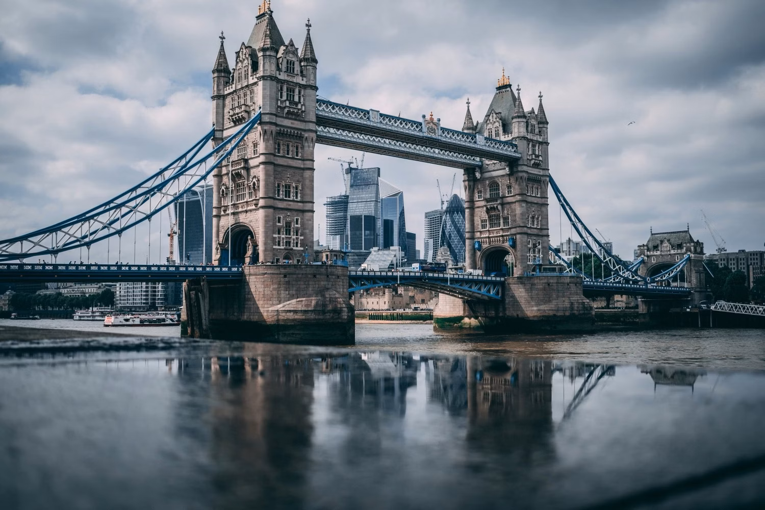 Tower Bridge spanning the River Thames with London’s skyline under a cloudy sky