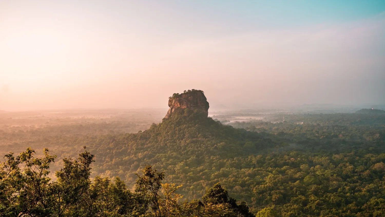 Lone flat-topped rock fortress rising above a misty green jungle at sunrise, Sigiriya-like landscape.
