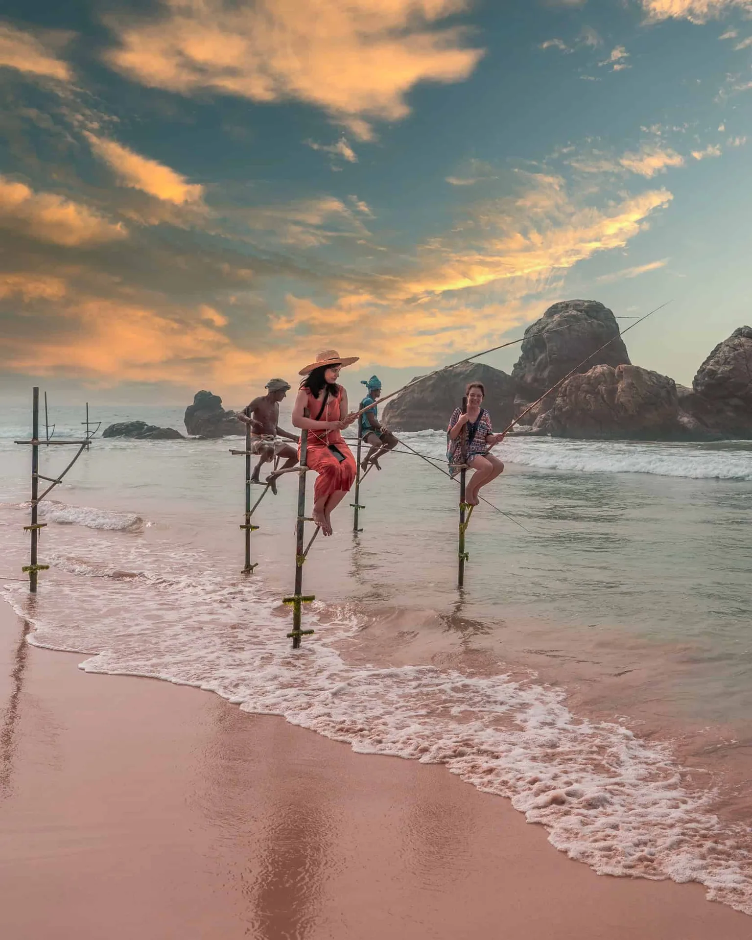 Fishermen balancing on stilts at sunset.