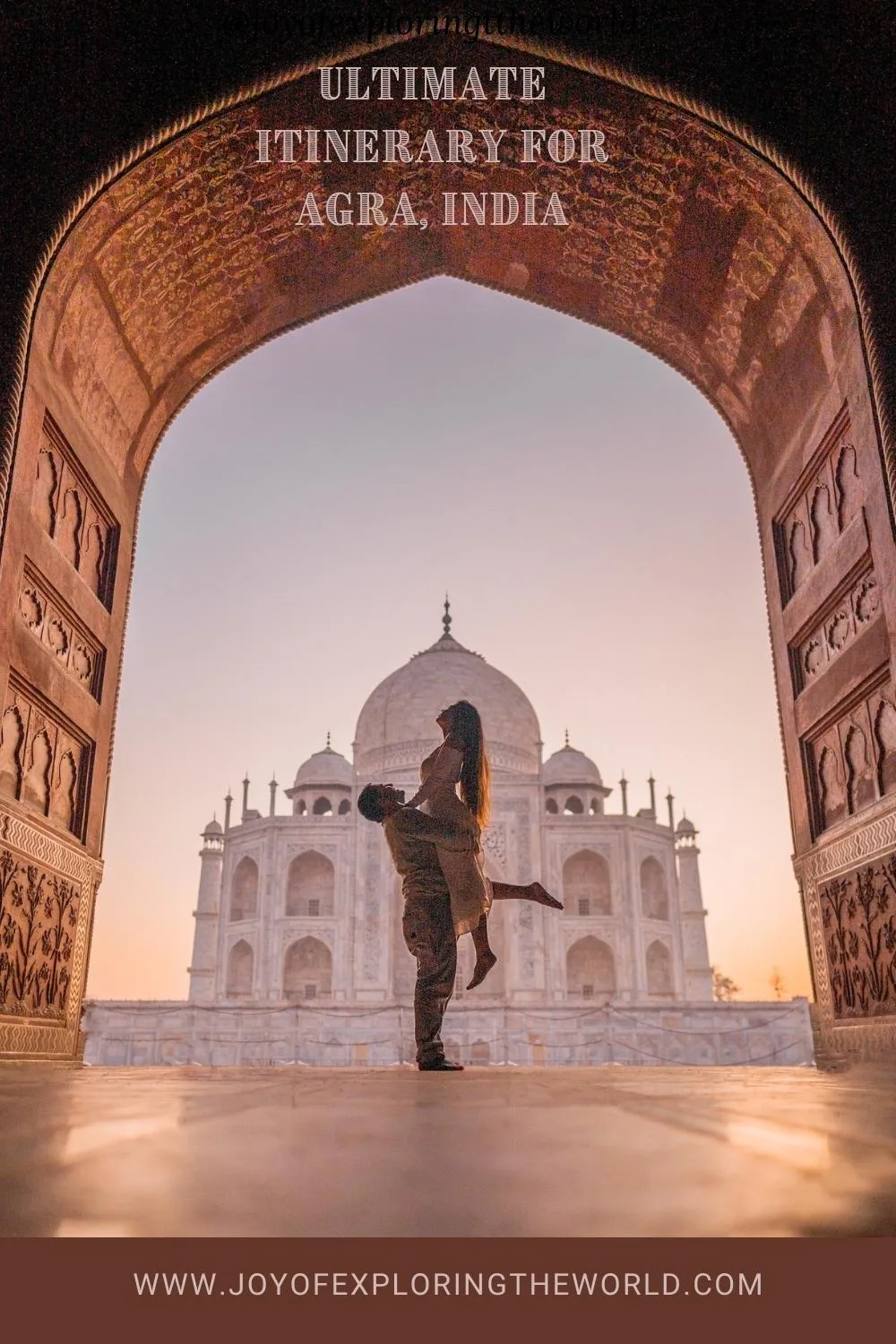 Couple silhouetted in an arched gateway embracing with the Taj Mahal bathed in soft sunrise light behind them.