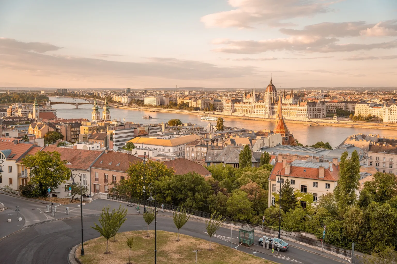 Panoramic view of Budapest at golden hour with the Danube River and the Hungarian Parliament building along its banks.