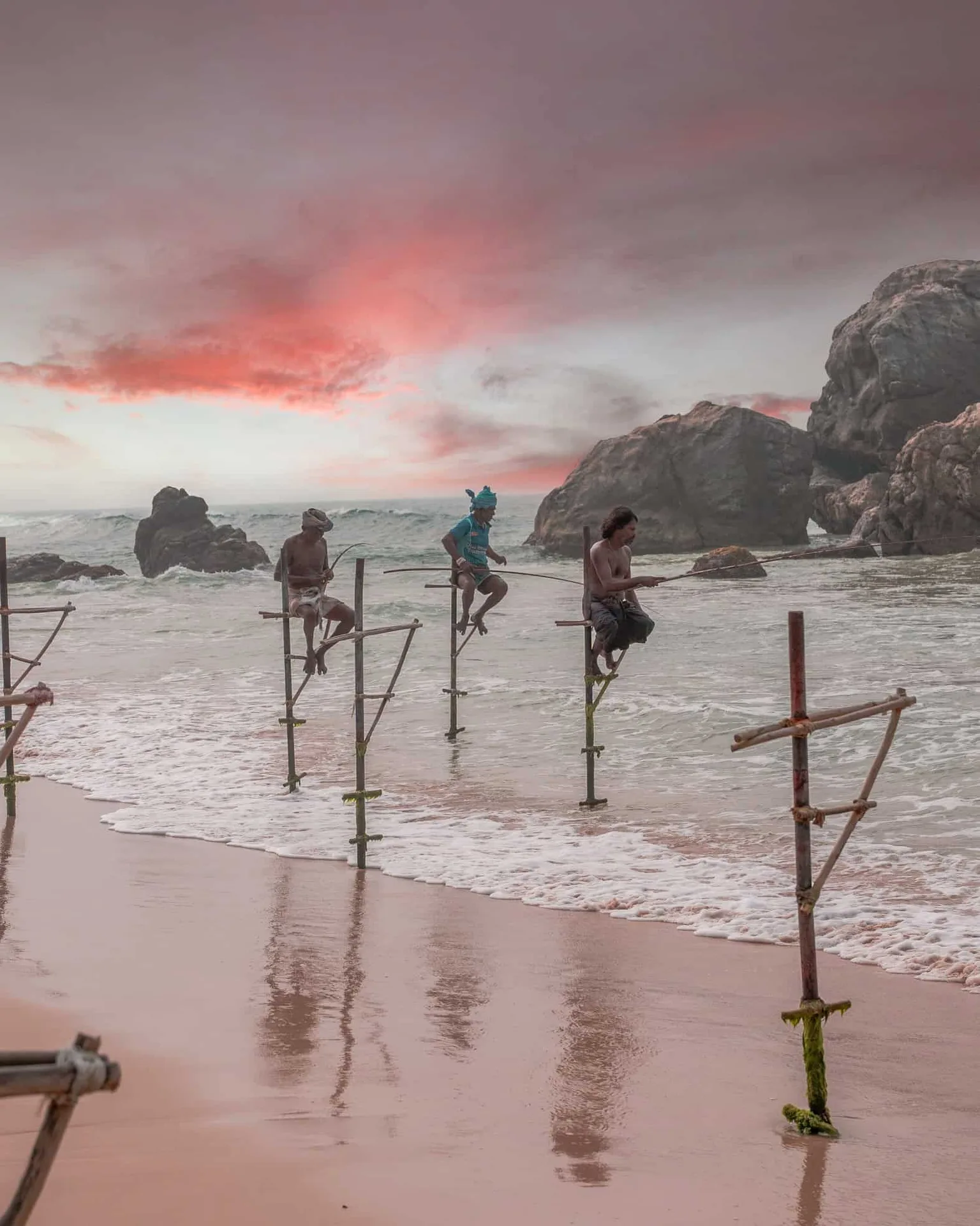 Fishermen stilt fishing at sunset.